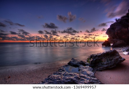 Landscape of Sunset on beautiful beach with rock as the foreground. Blue Purple and Orange coloring the sky during sunset using slow speed.