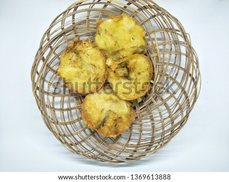 Delicious indonesian traditional snack  cake street or gorengan. ote ote  or bakwan or fried wheat dough filled vegetable fritter , On rattan plate craft homemade isolated on white background studio