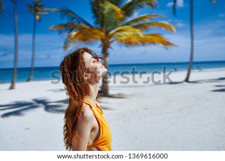 A woman in a yellow swimsuit is resting on the nature of white sand palm island       