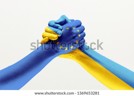 Brothers and friends. Two male hands holding colored in flag of European Unity and Ukraine isolated on grey studio background. Concept of help, partnership of countries, political and economical