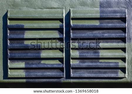 Camouflage surface of armored military vehicles with metal grill. Part of the armored personnel carrier. Texture of the khaki metal surface for background.
