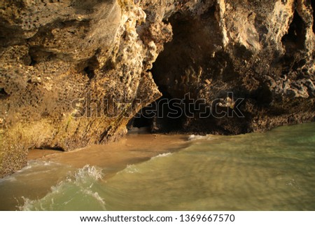 Small sea cave's entry through waves. Limestone cave in Phra Nang Beach in Railay in Thailand during golden hour.