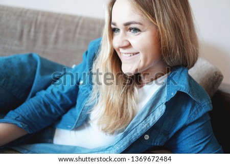 Home lifestyle woman relaxing enjoying sofa. Happy lady lying down on comfortable pillows daydreaming thinking. Beautiful young woman