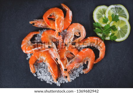 boiled shrimps on a dark gray background with lemon and parsley, top view