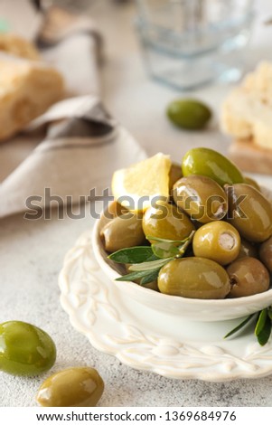 Bowl with tasty olives on grey background