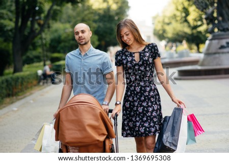 Beautiful family in a summer city. Lady with shopping bags. Mother with a carriage