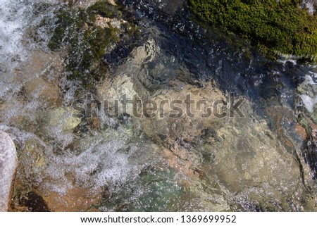 Water in the mountain raging river. Beautiful natural background of stones and water. Texture of clear water and fast river. Background to insert text.
