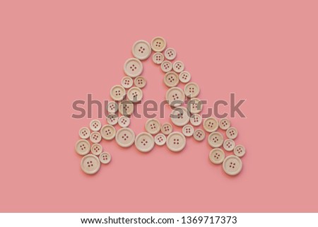the letter from the wooden buttons on a delicate pink background