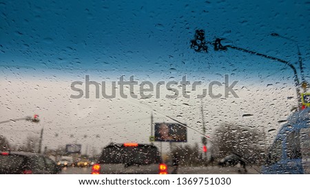 raindrops on blue windshield while standing on traffic light