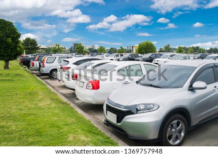 Car parking in parking lot. Row of white cars parked at outdoor  parking lot near grass pavement, white cloud and blue sky background

