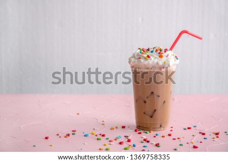 Cup of tasty frappe coffee on color table