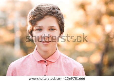 Smiling teen boy 14-15 year old wearing pink shirt posing over nature background. Looking at camera. Childhood.  Royalty-Free Stock Photo #1369781666