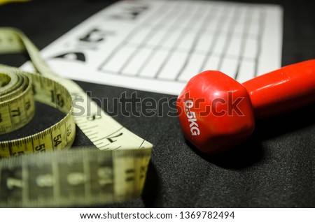 nutrition plan with measuring tape and red dumbbell background. Diet and loosing weight control concept. Handmade table for each day of the week. Fitness item and workout equipment.