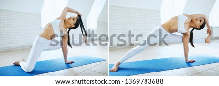 Sporty attractive woman in white sportswear working out indoors against white wall. Athletic female showing how to do arm balance Visvamitrasana, Visvamitra's Yoga Pose wiht a strap. Healthy lifestyle