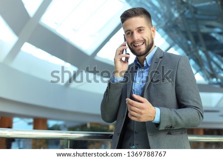 Young smiling businessman calling on phone at office.