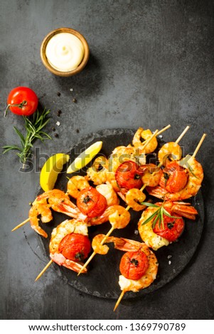 Grilled seafood. Delicious Grilled tiger shrimps with tomatoes, lemon and sauce served on a slate board. Seafood. Top view flat lay background.