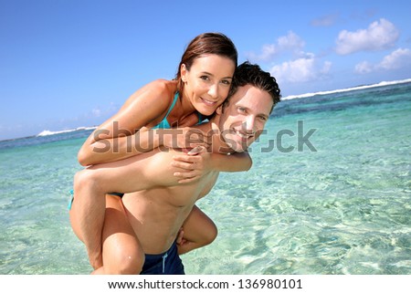 Man giving piggyback ride to girlfreind in Caribbean sea