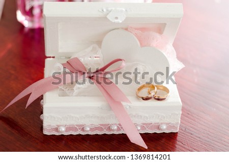 This photo shows wedding rings, a box for rings, as well as decorated champagne bottles.