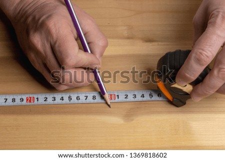 Carpenter with a pencil marks the blank for furniture made of wood
