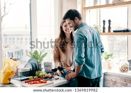 He will never let her go. Beautiful young couple cooking dinner and drinking wine while standing in the kitchen at home Royalty-Free Stock Photo #1369819982