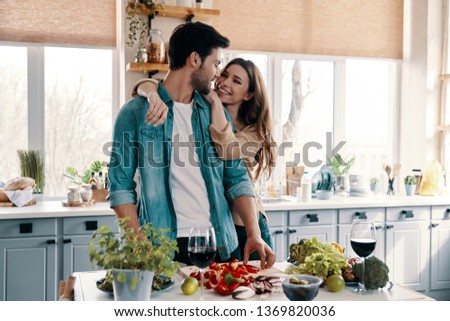 Enjoying time together. Beautiful young couple cooking dinner while standing in the kitchen at home Royalty-Free Stock Photo #1369820036