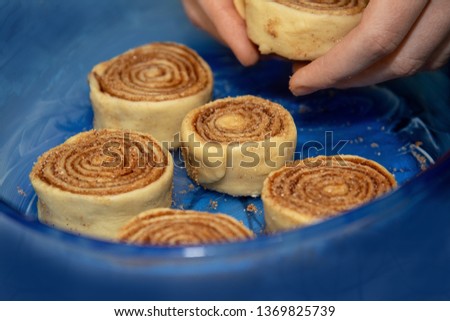 Billet cinnamon rolls are placed in a blue transparent baking dish.