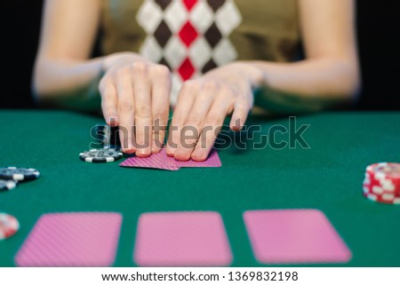 Female hands lay out playing cards and chips in a casino on a green table