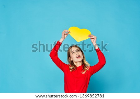 Beautiful glamor woman holding in her hands a yellow red heart blue background