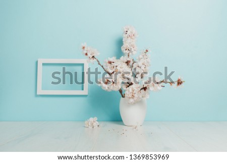 Spring bouquet in a white vase, white frame on the table. Mockup