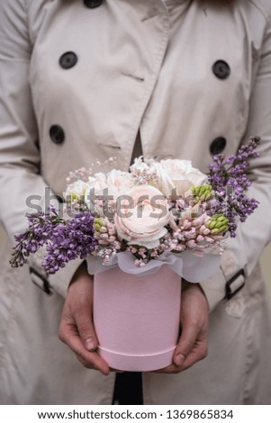 Woman florist making a lovely pastel flower composition in round box in a flower shop