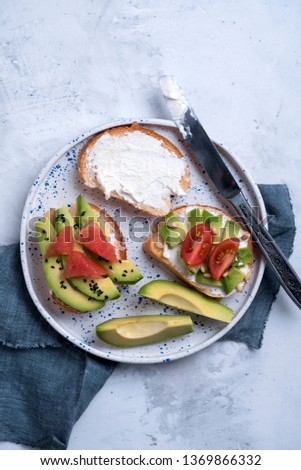 Toasts with avocado, tomatoes and cream cheese on a white plate. Breakfast or lunch concept Royalty-Free Stock Photo #1369866332
