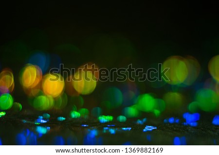 Defocused colorful bokeh circles on dark background. Lens flare illuminated glow. Abstract design.