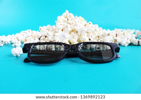 Concept pastime, entertainment and cinema. Popcorn and 3d glasses on blue background.