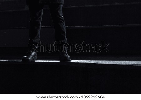 Dramatic close-up of legs of the man on the stairs. Theatrical, dark, night scene. 