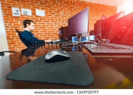 Close-up of a mouse for pc on the table on the background of programmer who is working on a computer. IT company office. Website design. Programming.