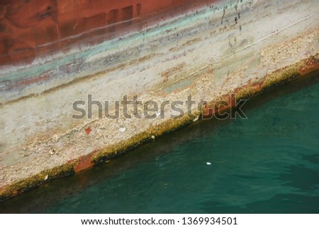 Metal rusty bottom of the ship. Texture of old painted metal. The bottom of the ship in the green sea mud. Water transport.