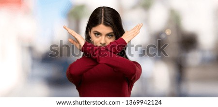 Teenager girl with turtleneck making NO gesture at outdoors