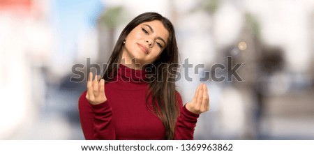 Teenager girl with turtleneck making money gesture at outdoors