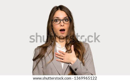 Business woman surprised and shocked while looking right over isolated grey background