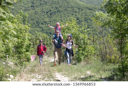 Family with two daughters travels along a beautiful path in the forest