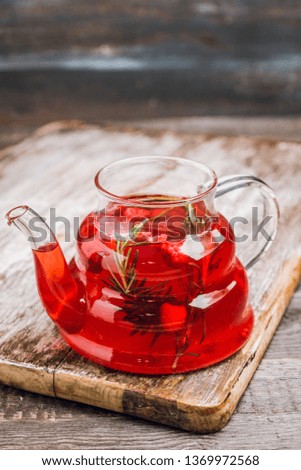 Hot raspberry beverage with rosemary in glass teapot. Selective focus. Shallow depth of field.
