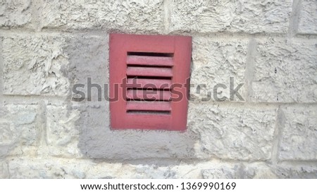 Texture, background, wallpaper, burgundy iron or metal grate image in a gray concrete wall in a house or building on a clear day.