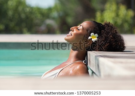 Young black woman relaxing at spa pool. Beautiful woman relaxing in outdoor spa swimming pool with head leaning at poolside. Closeup face of attractive girl with closed eyes enjoy vacation at resort. Royalty-Free Stock Photo #1370005253