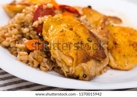 Closeup  of tasty  chicken thighs with pearl barley  at plate on table
