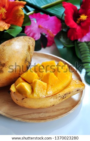Close up pieces of ripe mango on wooden plate with tropical concept on background