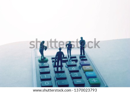 Miniature people on a desktop calculator. Certified accountants or financial planning team in a meeting.  Group of professional men and women crunching numbers under a deadline.Modern tax pros working Royalty-Free Stock Photo #1370023793