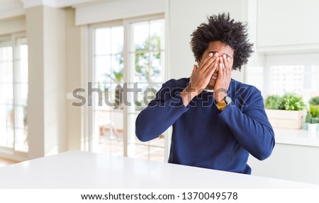 Young african american man wearing casual sweater sitting at home rubbing eyes for fatigue and headache, sleepy and tired expression. Vision problem