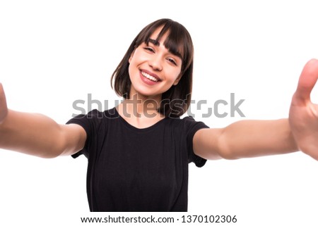 Studio portrait of beautiful woman smiling with white teeth and making selfie, photographing herself over gray background