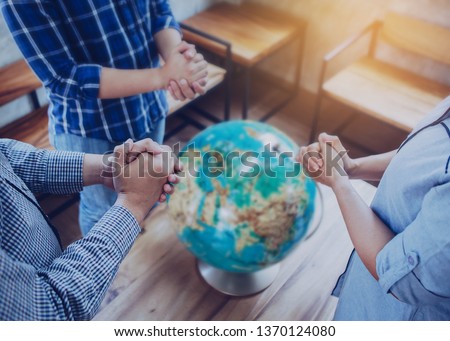 Three people standing and pray to God for the world with blurred world globe on wooden table, Christian background for great commission concept. Royalty-Free Stock Photo #1370124080