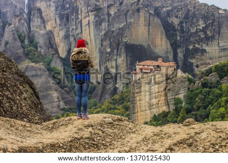 travel woman back to camera take photo by phone mobile device in hand from beautiful European rocky highland scenic landscape with monastery religion building on top of rock in Greece
